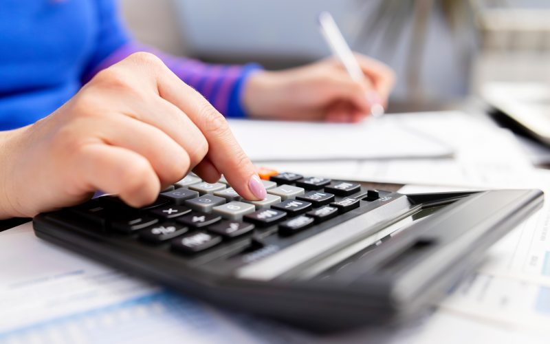 Woman using calculator for calculate taxes at home, doing paperwork
