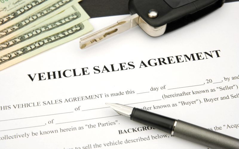 Vehicle Sales Agreement with car key and money and document and pen