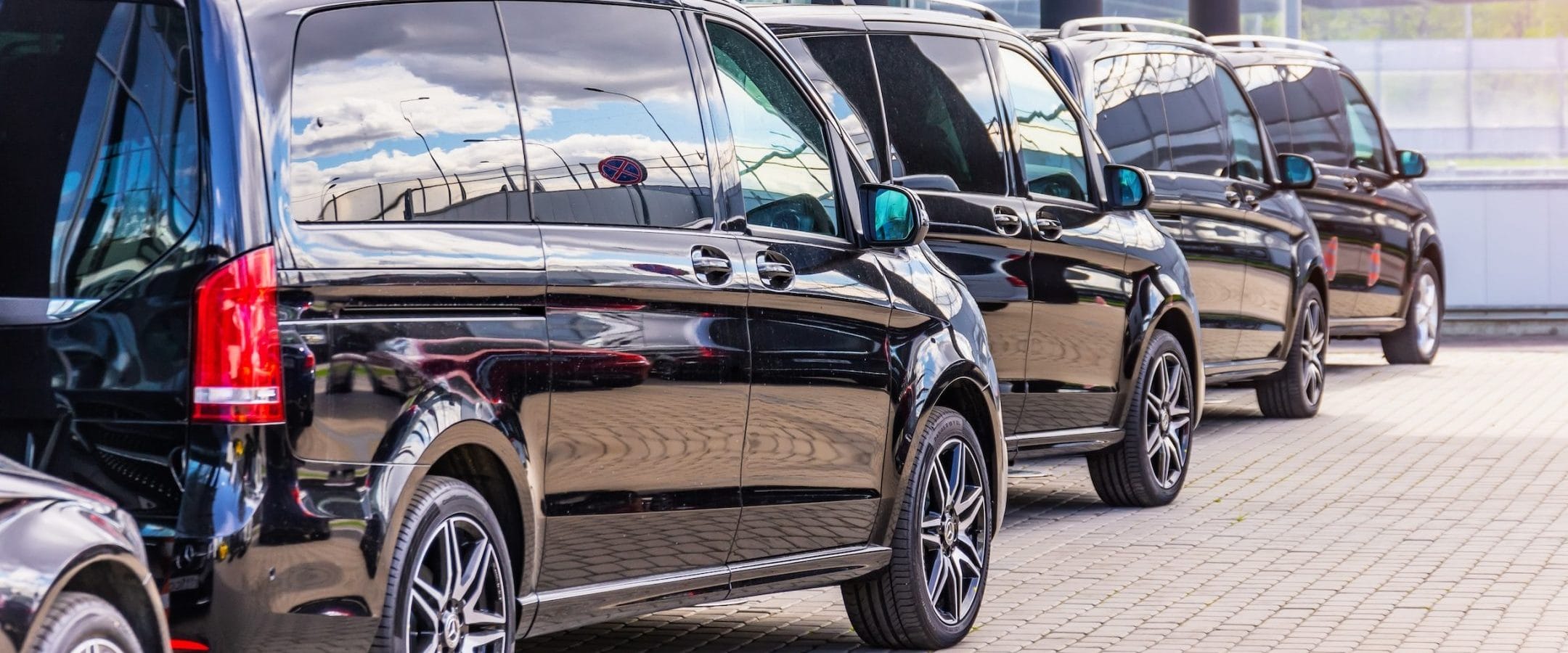 lineup of black minivans in a parking lot
