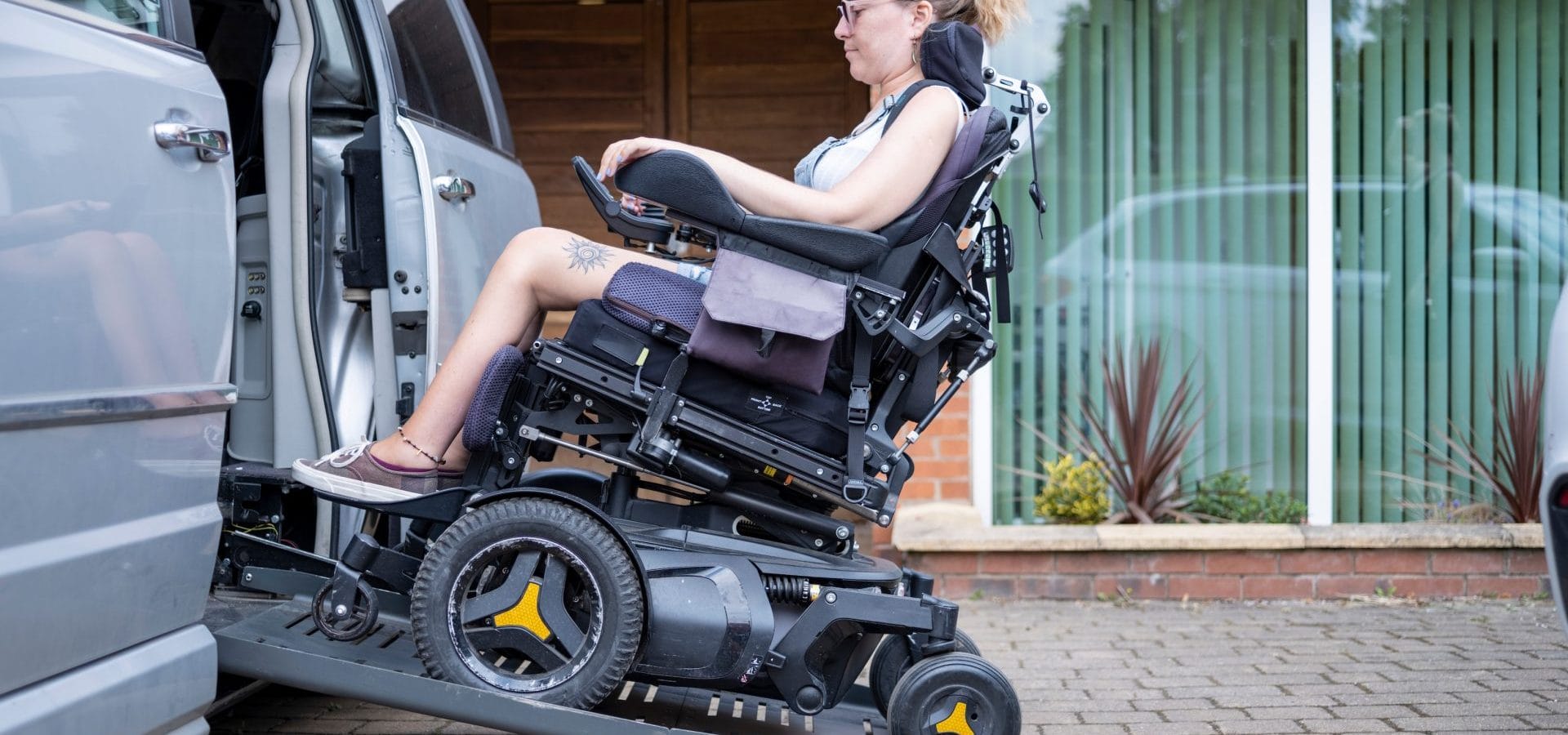 Woman in an electric wheelchair entering a side entry ramp of a minivan.