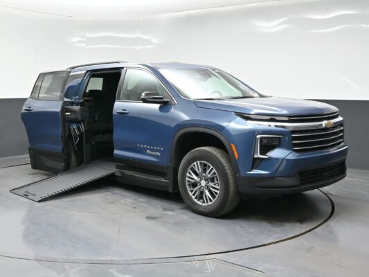 Blue Chevrolet Traverse SUV with the rear door open and a deployed wheelchair ramp extending from the vehicle. BraunAbility logo visible on the side panel.