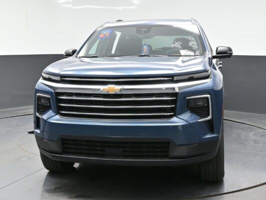 Front view of a blue Chevrolet SUV in a showroom, showcasing the chrome grille and gold bowtie emblem.
