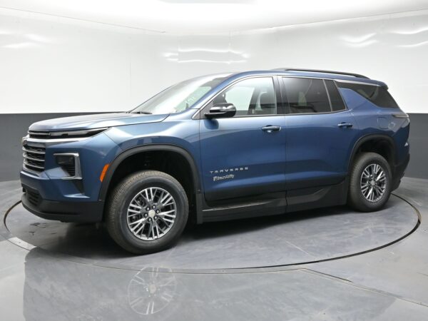 Blue Chevrolet Traverse SUV in a showroom, side view with visible wheel and model badge on the door.