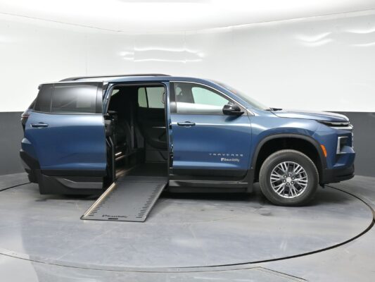 Blue SUV with a side-entry wheelchair ramp extended from the rear passenger area, in a showroom (BraunAbility branding visible).