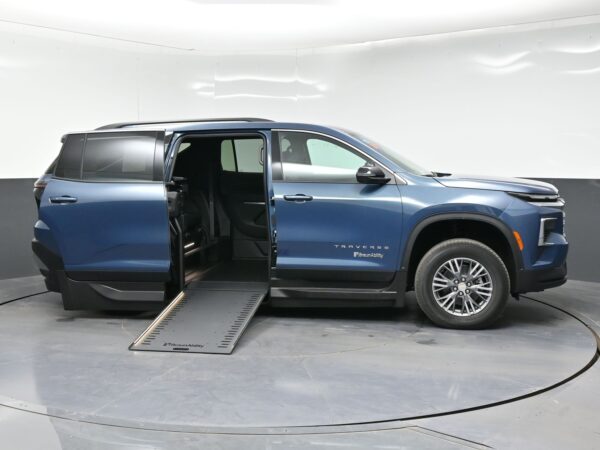 Blue SUV with a side-entry wheelchair ramp extended from the rear passenger area, in a showroom (BraunAbility branding visible).