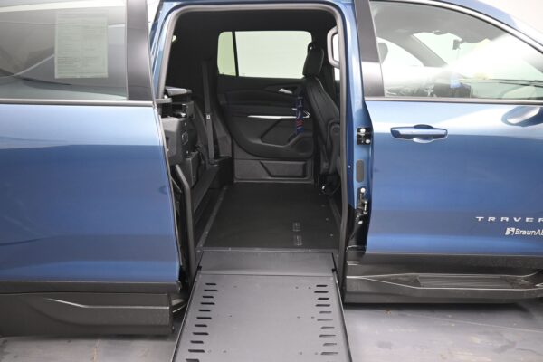 Blue wheelchair-accessible van with the ramp deployed and side door open, showing the interior and seating area.