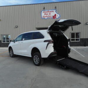 White SUV with a deployed wheelchair ramp in a parking lot in front of a gray industrial building with a Southern Bus & Mobility sign nearby.