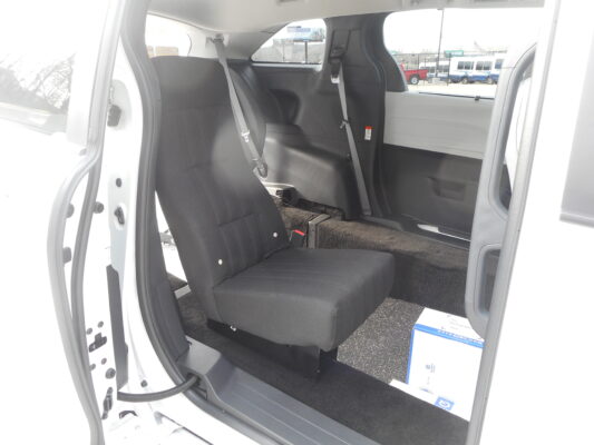 Interior of a white van showing the rear bench seat with three seat belts and an open side door