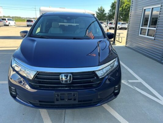 Front view of a dark blue Honda SUV parked in a dealership lot, with the Honda emblem on the grille and headlamps visible beneath a clear sky into the lot area.