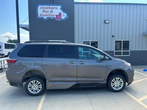 Passenger side Gray minivan parked in a lot in front of a mobility center with a 'Southern Bus & Mobility' sign in the background, ready for accessibility services.