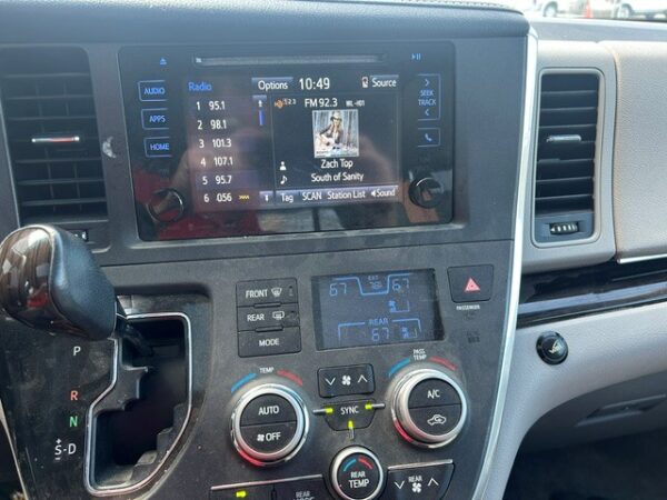 Radio, AC Center console of a car showing a touchscreen infotainment display (radio) with climate controls below and a gear shifter to the left.