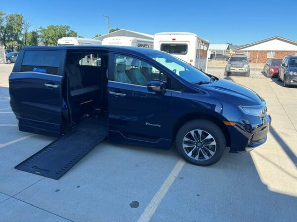 Ramp out (3) Blue minivan with a side-entry ramp extended for wheelchair access, doors open in a parking lot.