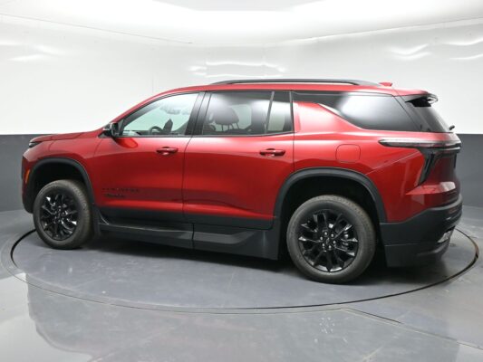 Side view of a red SUV with black wheels parked in a studio backdrop, showing roof rails and tinted windows.