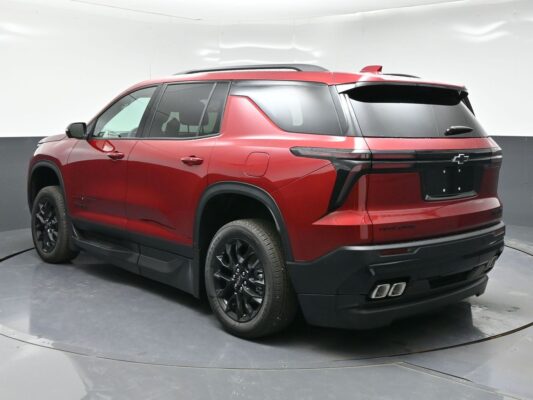 Red Chevrolet Tahoe SUV shown from the rear-left side, highlighting black wheels, roof rails, and sculpted rear end with dual exhausts