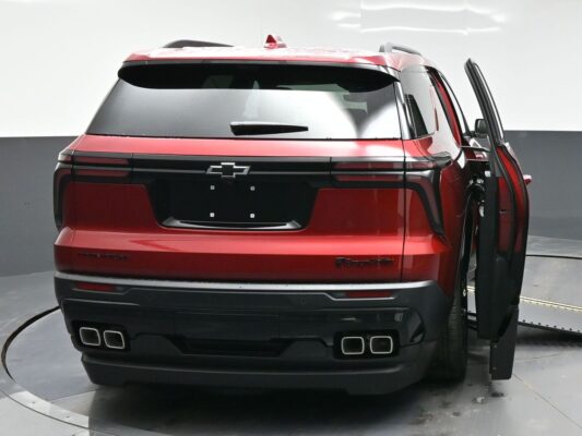 Rear view of a red Chevrolet SUV on a turntable, with the right-side rear door open and black bumper accents visible.