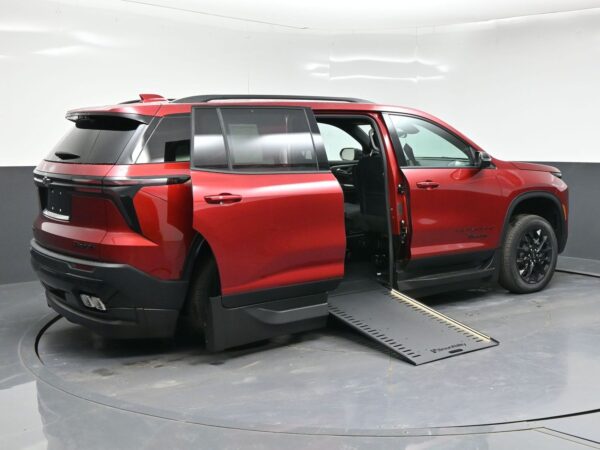 Red SUV with a side-entry ramp lowered and door open, showing a wheelchair-accessible modification in a showroom setting.