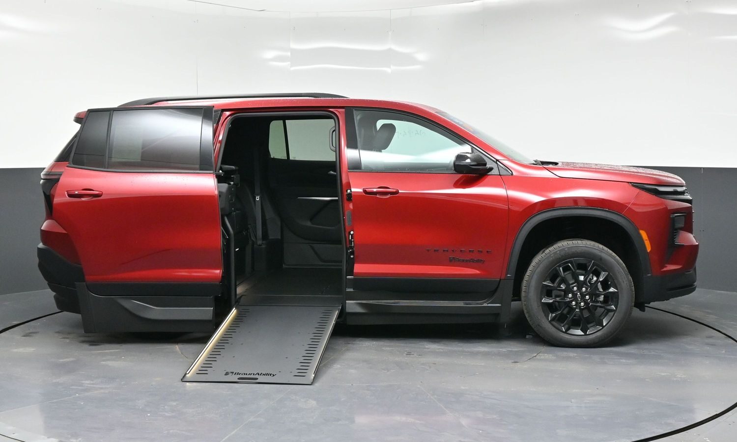 Red minivan with a lowered side ramp for wheelchair access and doors open, showing the interior seating area.