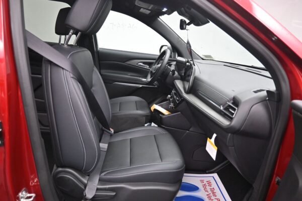 Front interior of a red car with black leather seats and white stitching, showing the dashboard, steering wheel, and center console.