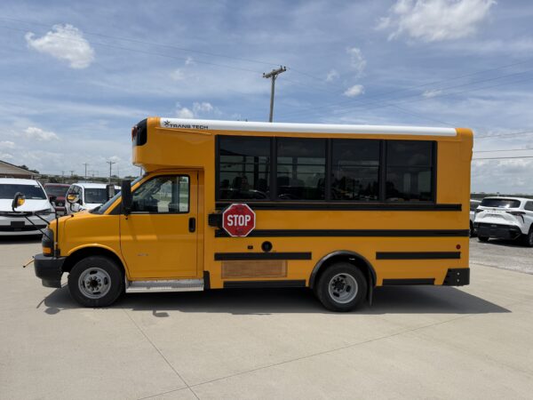 Yellow school bus with a stop sign on the side, parked in a lot under a blue sky with power lines in the background.