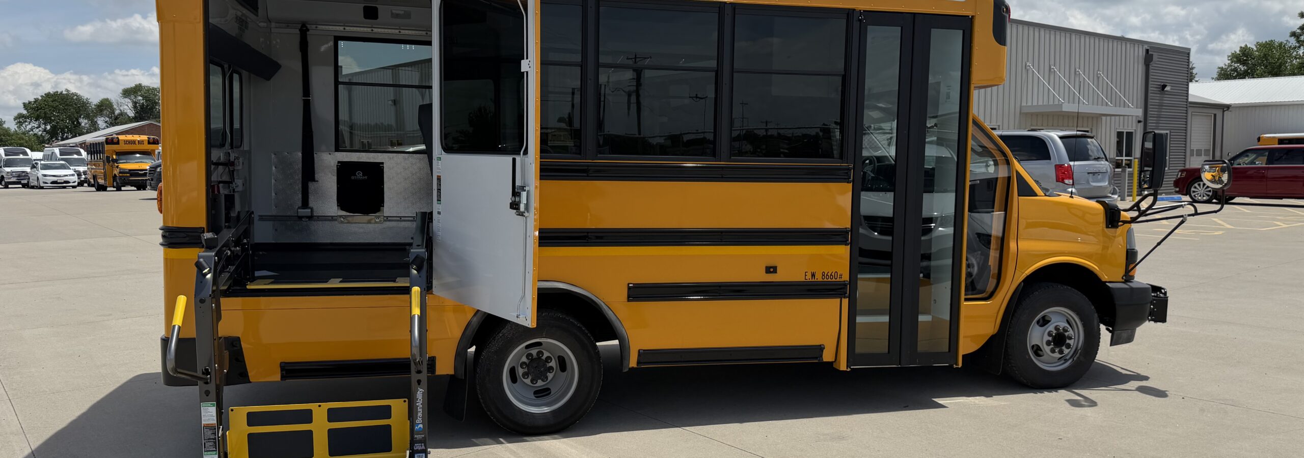 Yellow school bus with a lowered wheelchair ramp extended for accessible boarding in a sunny parking lot