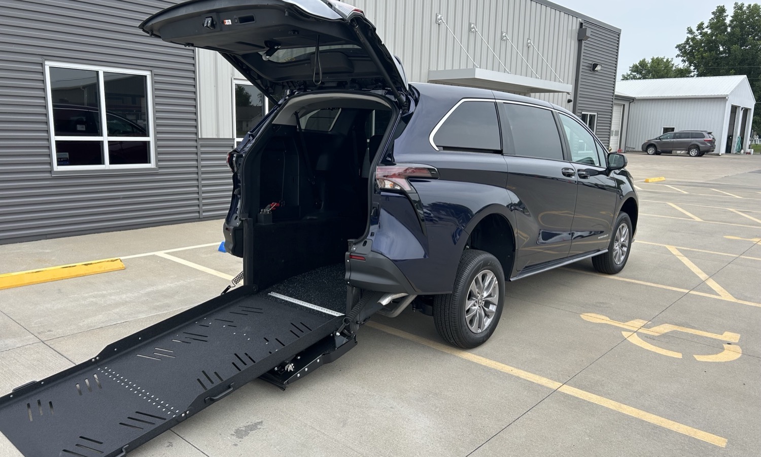 SUV with a lowered rear ramp, ready for wheelchair access in a parking lot.