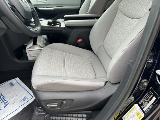 Front interior of a car showing the driver seat and center console with cupholders and armrest.