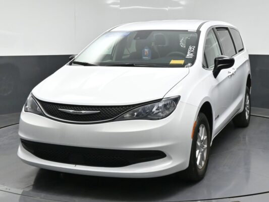 White Chrysler minivan photographed from the front-right in a studio, showing the grille, headlights, and alloy wheels.