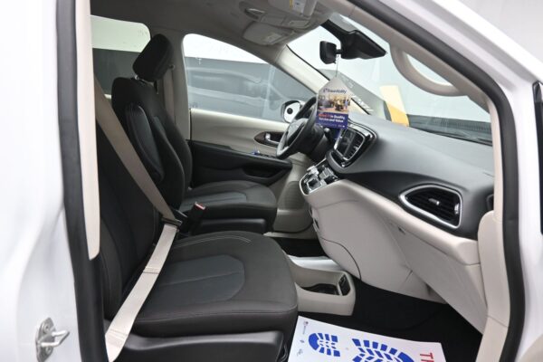 Interior of a white car showing driver and passenger seats, dashboard, and hanging BraunAbility tag.