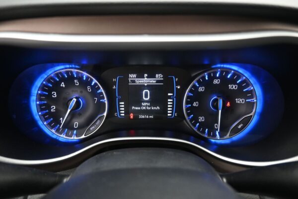 Blue-lit car instrument cluster with tachometer left, speedometer right, and central display showing 0 mph and 33,616 miles (idle)