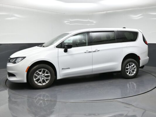 White minivan in a studio setting, shown in a side view with BraunAbility branding on the front door panel