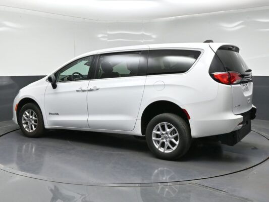 White minivan photographed in a studio, showing a three-quarter rear view with sliding door and alloy wheels.