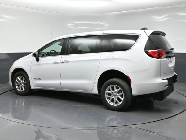 wav-2C4RC1CGXRR118735-3 White minivan photographed in a studio, showing a three-quarter rear view with sliding door and alloy wheels.