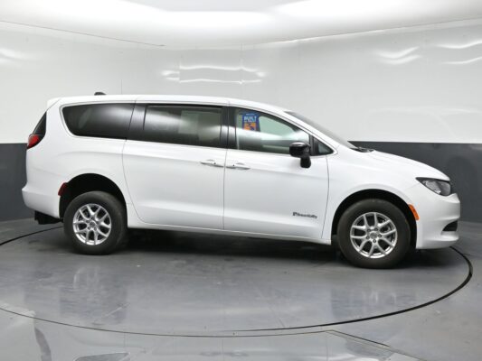 Profile view of a white minivan in a studio setting, BraunAbility branding on the front door area