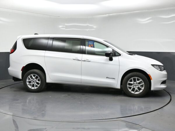 wav-2C4RC1CGXRR118735-7 Profile view of a white minivan in a studio setting, BraunAbility branding on the front door area