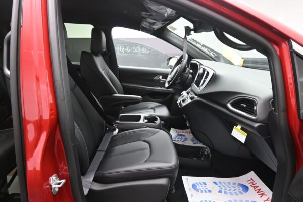 Red car interior with black leather front seats, center console, and steering wheel visible from the open door area.