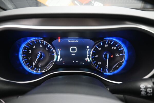 Car dashboard with center digital speed readout showing 0 MPH and blue-lit gauges on either side