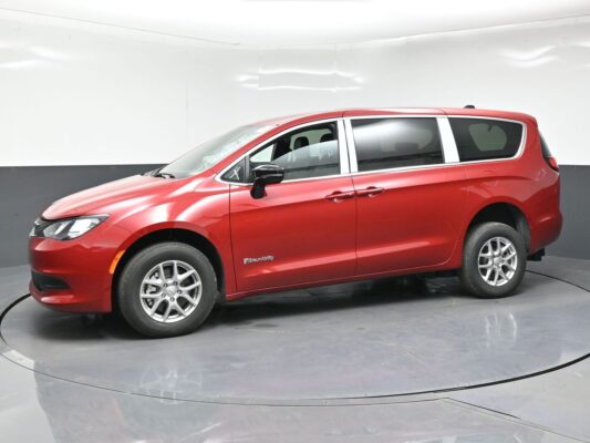 Red BraunAbility minivan with sliding doors and tinted windows, parked in a studio.