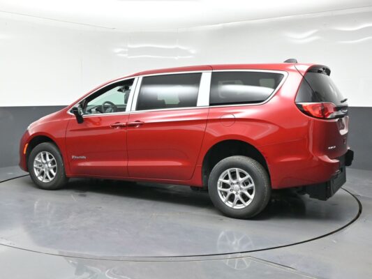 Red BraunAbility wheelchair-accessible minivan seen from the side in a studio setting.