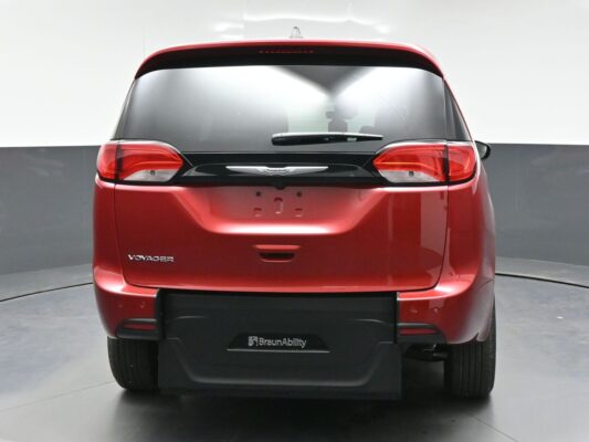 Rear view of a red Chrysler Voyager minivan with BraunAbility branding on the rear bumper, shown in a studio setting.