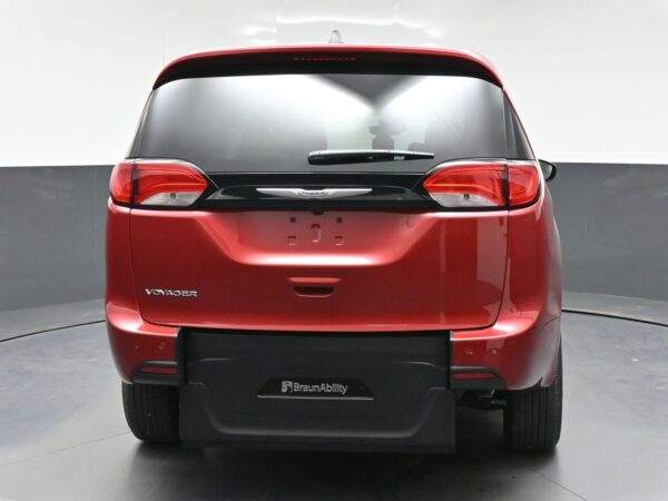 Rear view of a red Chrysler Voyager minivan with BraunAbility branding on the rear bumper, shown in a studio setting.