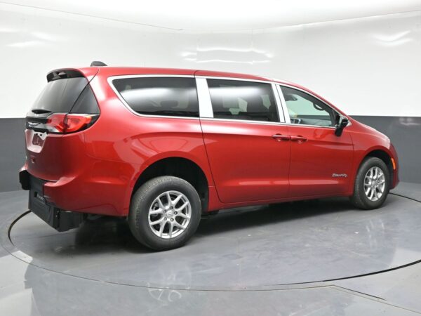 Red Chrysler Pacifica Hybrid minivan photographed in a studio on a rotating turntable, showcasing the side and rear profile with tinted windows and alloy wheels.