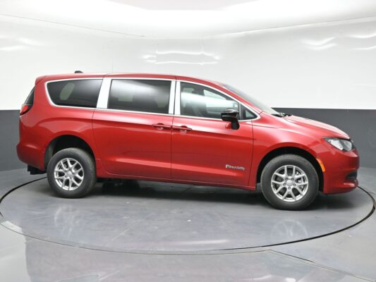 Side view of a red BraunAbility minivan on a circular display turntable in a studio setting.