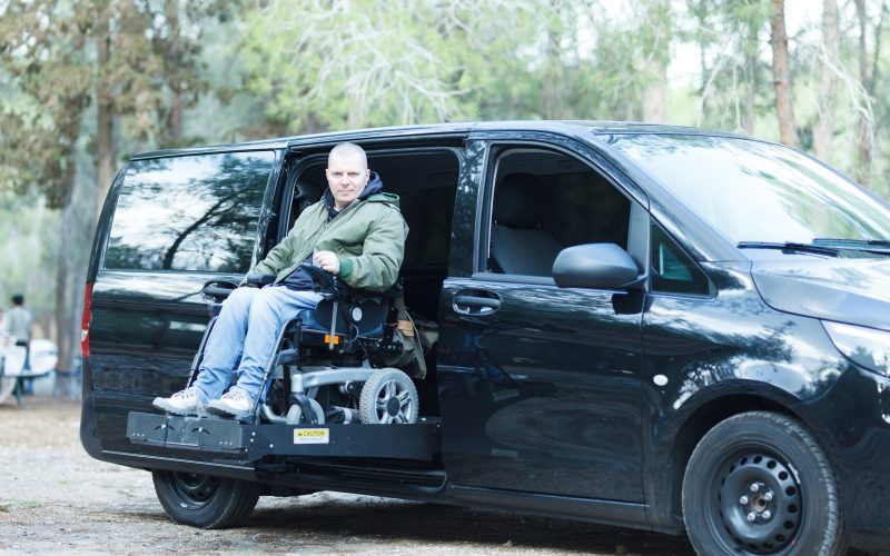 Disabled man on wheelchair on the car lift of an accessible passenger vehicle.