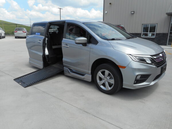 DSCN0019 Silver minivan with a lowered side ramp and open sliding door, parked outside a building.