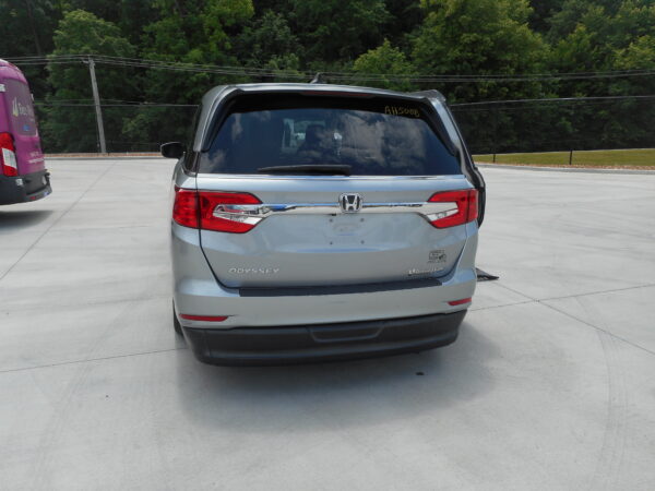 DSCN0022 Rear view of a silver Honda Odyssey minivan in a paved parking lot, with green trees in the background.