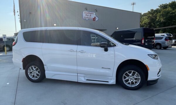 IMG_0396 White BraunAbility wheelchair-accessible minivan, side view, parked in a lot near a mobility dealership sign reading 'Southern Bus & Mobility'