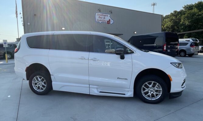 White BraunAbility wheelchair-accessible minivan, side view, parked in a lot near a mobility dealership sign reading 'Southern Bus & Mobility'