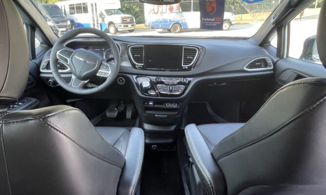 Interior of a modern car showing the front seats, steering wheel, and center console with a large infotainment screen
