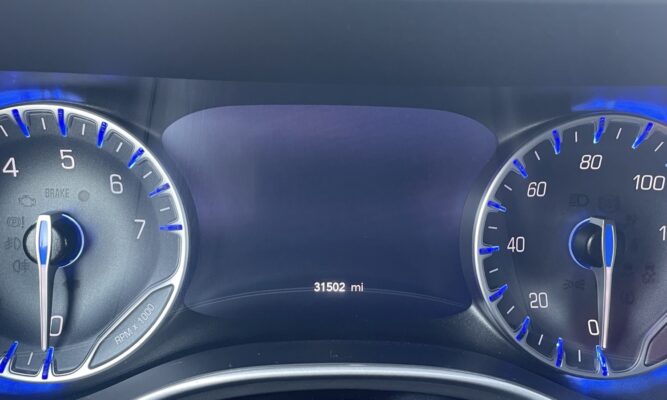Car dashboard with tachometer on left, speedometer on right, center display showing 31,502 miles.