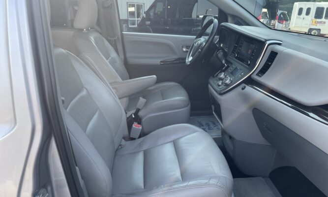Interior of a vehicle showing light gray leather front seats, steering wheel, and center console.